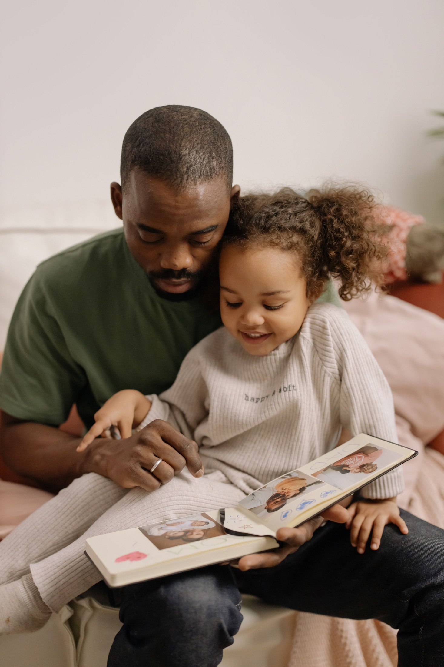 Un padre y su hija miran juntos un álbum de fotografías.